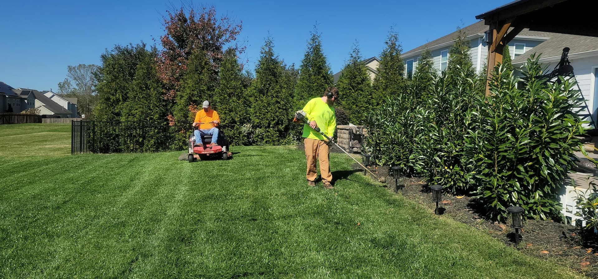 Crew mowing and edging a residential lawn in a leafy suburb